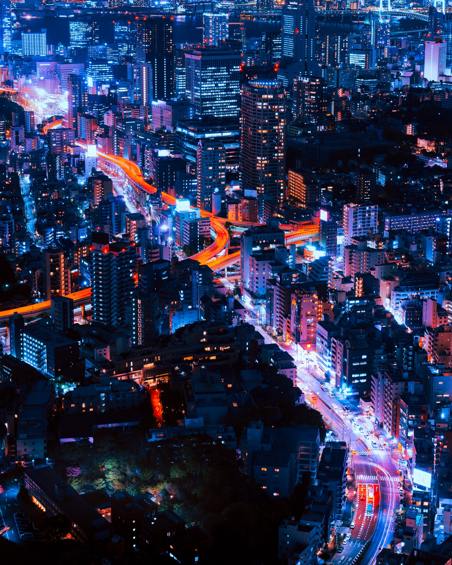 Vastly connected world - sky view of a city at night with lights in buildings and vehicles buzzing around
